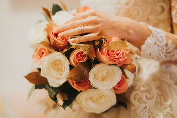 Canvas Print - Bride's hand holding a beautiful bouquet with white and orange roses