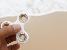 Cropped Hand Holding Fidget Spinner At Beach