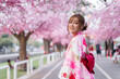 © geargodz - woman in yukata (kimono dress) looking sakura flower or cherry blossom blooming in garden