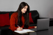 © Bhaven - Portrait of a young Indian woman working from home, Young student writing notes in her diary while studying from home.