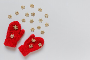 Little red kids mittens with many small wooden decorative white snowflakes and copy blank space on white background.