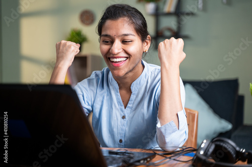 young business woman got overjoyed by good news and started celebrating while working on laptop - Concept of new Job offer or promotion, college admission and loan approvel or won the price money.