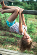 © De Visu - Little girl hanging upside down on green rural countryside.