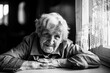 © De Visu - An elderly woman pensioner sitting at the table. Black and white photo.