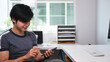 © Prathankarnpap - Young Asian man freelance sitting at his modern home office and using smart phone.
