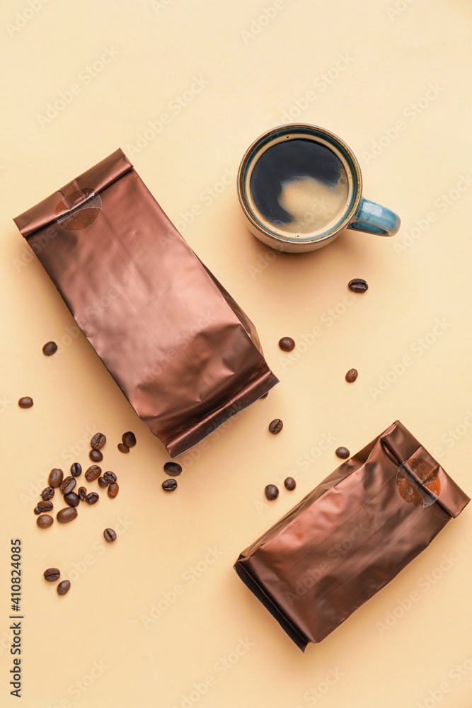 Foil bags and cup of hot coffee on light background