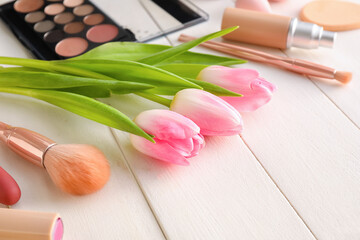 Cosmetics and spring flowers on white wooden background