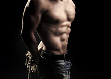 Strong Young Man With Muscular Body With Tied Hands By Rope Standing In Studio On Black Background.
