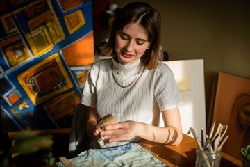 young artist moulding raw clay in art studio. Girl molds from clay sculpture in the artist's studio. Business woman at her pottery store