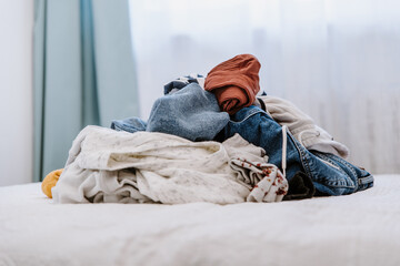 Wall Mural - Pile of unfolded dirty clothes for laundry on the bed. Heap of used clothes for donation and recycling. Concept of minimalism, mess and wardrobe cleaning