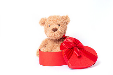 teddy bear sitting in a heart shaped box isolated on a white background