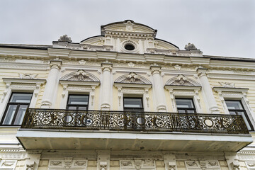 An element of the facade of a historic building in Tobolsk (Russia) with many architectural elements, stucco moldings, patterns, people and animals. balcony with patterned cast grating. Close-up