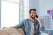 © IndiaPix - Young man sitting on the couch and talking on the phone.