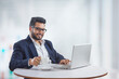 © IndiaPix - Young man sitting in his office while working on the laptop while drinking coffee.