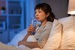 © Syda Productions - people, bedtime and thirst concept - asian woman drinking water at night in bed at home
