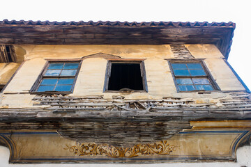 View od ruins of a historic house from below in Old Town, Antalya, Turkey. Beautiful exterior design and broken windows of an abondoned house and art work under the window.