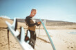 © merla - Handsome senior man getting ready to go surfing in the sea