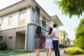 Asian woman Real estate broker agent showing a house detail in her file to the young Asian couple lover looking and interest to buy it. Buying a new house..