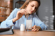 © New Africa - Woman putting medicine for hangover into glass of water in office, focus on hands