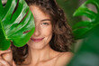 Beauty natural woman covering her face with tropical leaf
