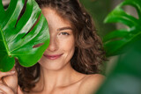 Fototapeta  - Beauty natural woman covering her face with tropical leaf