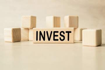 the word INVEST is written on a wooden cubes structure. Cube on a bright background. Can be used for business, MEDICINE, financial concept. Selective focus.