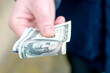© сергей тарануха - the hand holds out several hundred dollar bills folded in half