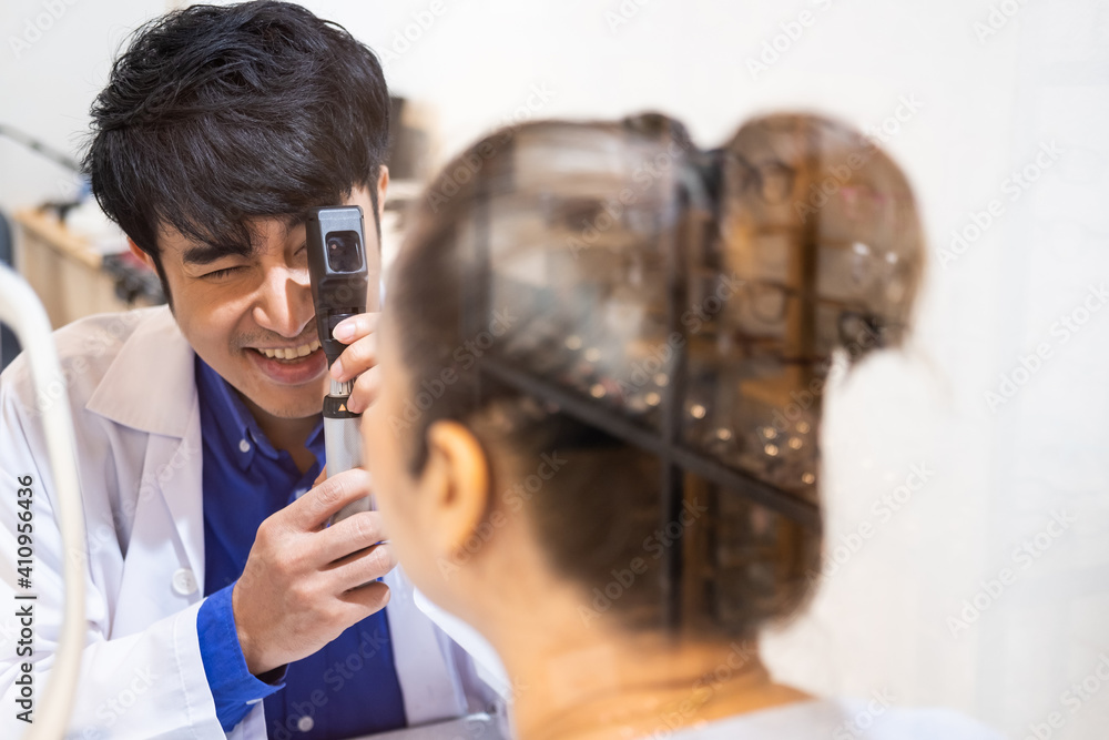 Scripted Optometry Selective focus at Optometrist face. While doctor using penlight and ...