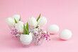 Easter holiday decoration in eggshell white tulips and pink gypsophila and two white eggs on pink pastel background. copy space.