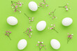 White Easter Eggs on green background with pink gypsophila , Fun Easter flat lay.
