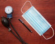 medical blue mask with pen and manual blood pressure reader with wood background representing work of doctors