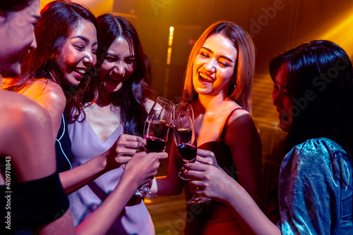 Young people celebrating a party, drink and dance . Group of friend toasting drinks while having fun at the disco club at night . Friendship and nightlife concept .