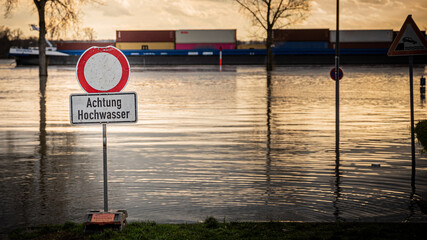 Schild Hochwasser an Straßensperrung mit Schiff im Hintergrund