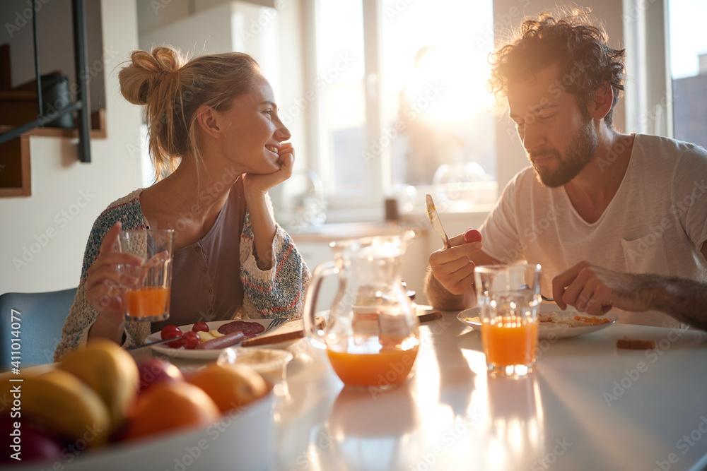 A happy young couple enjoying a beautiful sunny morning while having a breakfast together. Relationship, love, together, breakfast - obrazy, fototapety, plakaty 