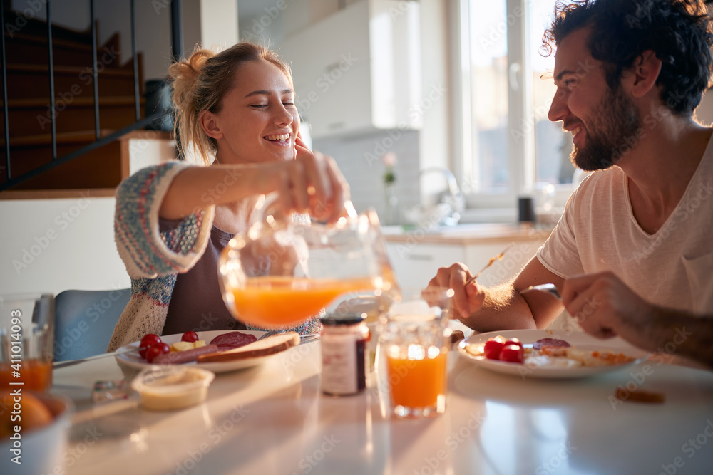 A happy young couple enjoying fresh orange juice for a breakfast. Relationship, love, together, breakfast - obrazy, fototapety, plakaty 