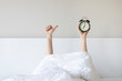 © Hazal - Woman showing arm raised up holding coffee cup behind duvet in the bed room, Young girl with two hands sticking out from the blanket. wake up with fun in morning concept.