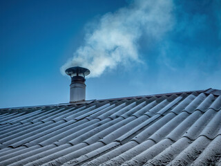 Chimney emits smoke against the blue sky