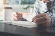 © tippapatt - Casual man hand with a pencil writing on paper notebook on wooden table during working from home