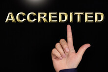 ACCREDITED Text, A Word Written On A Black Background Pointed To By A Hand With The Index Finger Of A Person.