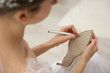 © New Africa - Young bride writing on her shoe indoors, closeup. Wedding superstition
