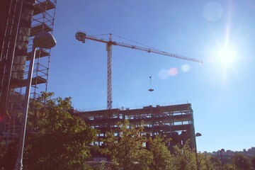 Un edificio en construcción en el barrio de Montecarmelo, Madrid, España. Grúa de construcción, andamios y redes de protección en un día de trabajo.