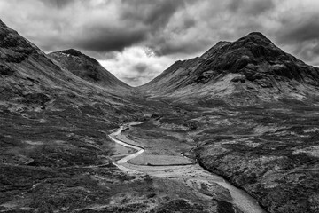 Wall Mural - Flying drone epic  black and white landscape image of mountains rivers and valleys in Glencoe in Scottish Highlands on a Winter day