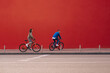 © bodnarphoto - Stylish couple man and woman ride bicycles on the background of a red wall in sportswear. Urban lifestyle photo of a cyclist on a weekend walk