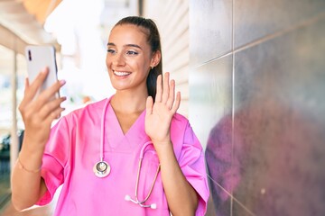 Wall Mural - Young hispanic doctor woman speaking on the smartphone at street of city.