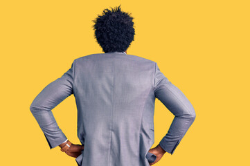 Handsome african american man with afro hair wearing business jacket standing backwards looking away with arms on body