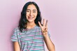 © Krakenimages.com - Hispanic teenager girl with dental braces wearing casual clothes showing and pointing up with fingers number three while smiling confident and happy.