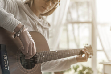 Young woman playing guitar at home