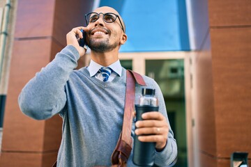 Poster - Young african american businessman smiling happy using smartphone at the city.