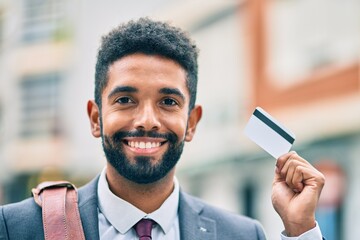 Poster - Young african american businessman smiling happy holding credit card at the city.