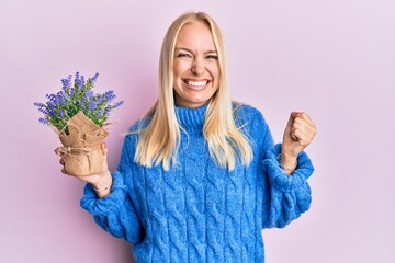 Poster - Young blonde girl holding lavender pot screaming proud, celebrating victory and success very excited with raised arm